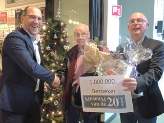 Voorzitter Robbert Brockhoff (l) en directeur Hans Stuijfbergen (r) feliciteren Han Hensen als miljoenste bezoeker