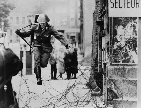 East German border guard Conrad Schumann leaps into the French Sector of West Berlin over barbed wire on August 15, 1961
